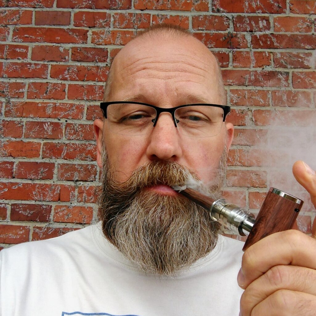 Yours truly vaping a wooden pipe in front of a brick wall