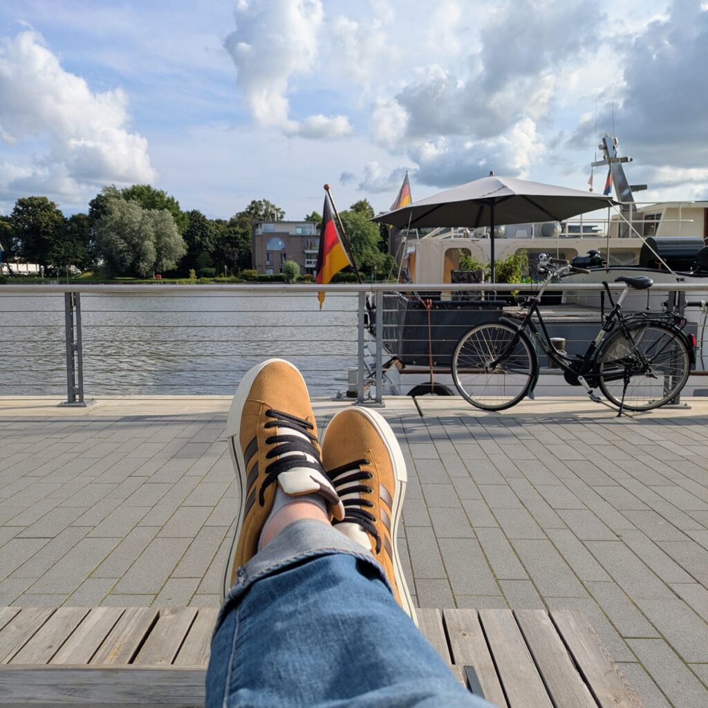 View on Leer harbour (port, get it?) with yours truly's feet in the foreground, brown Adidas trainers with white soles and black stripes